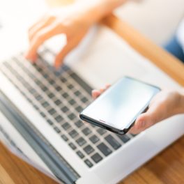 Business woman hand with Financial charts and mobile phone over laptop on the table